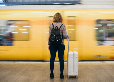 a woman stands still infront of a train rushing past in the background